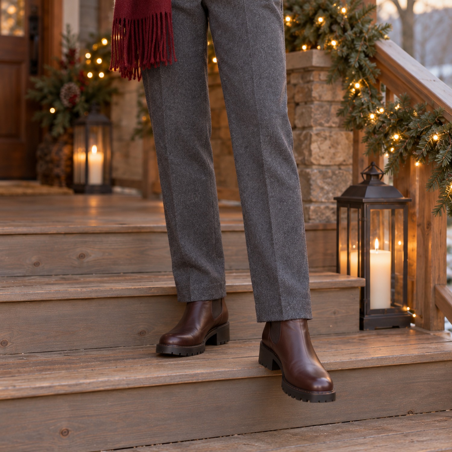 Charcoal straight-leg trouser hem skimming the top of a chocolate brown Chelsea ankle boot on a wood-plank porch